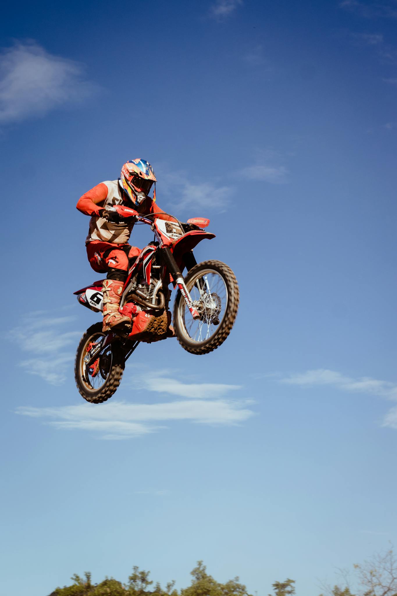 a thrilling motocross stunt captured mid air against a bright blue sky. 11120816