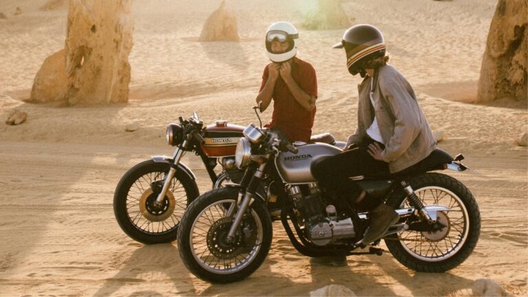 Two riders on vintage Honda motorcycles in a desert at sunset, capturing authentic user-generated motorcycle content and rider lifestyle.